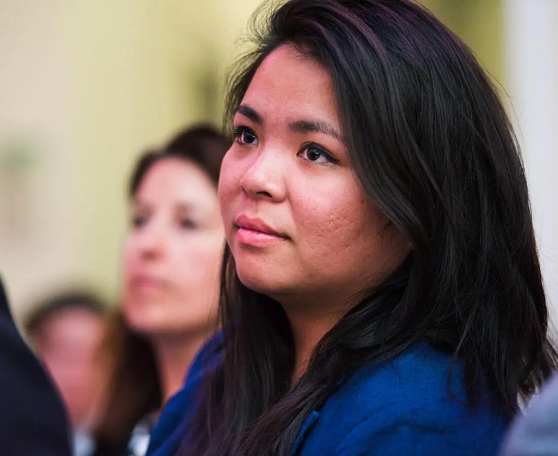 A closeup of a woman's face as she looks on during a presentation