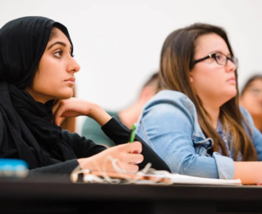 Undergraduate students taking notes in class.