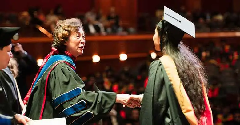 RBS Dean Lei Lei congratulates one of hundreds of graduate students who celebrated the completion of master's programs.