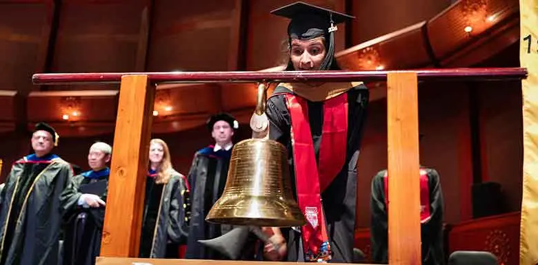 MBA student Anju Thottakara rings the school bell, a Rutgers Business School tradition. Thottakara served as president of the Student Government Association for graduate students in the Class of 2024. 