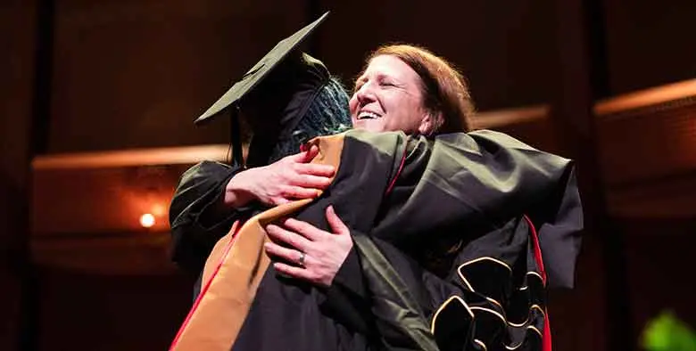 Professor Stacy Smollen-Schwartz congratulating a student.