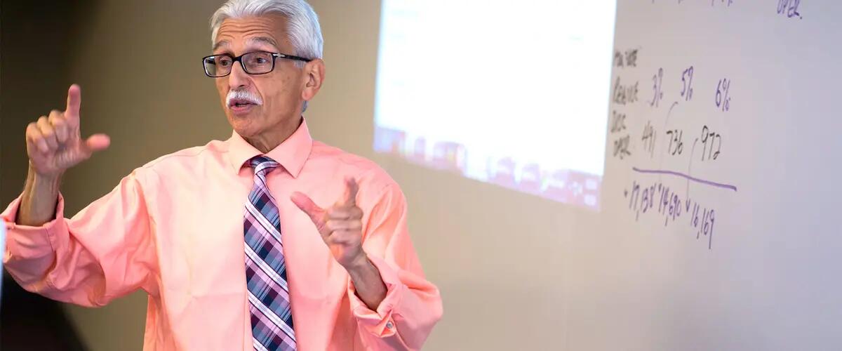 Professor Sanella infront of the whiteboard as he teaches passionately